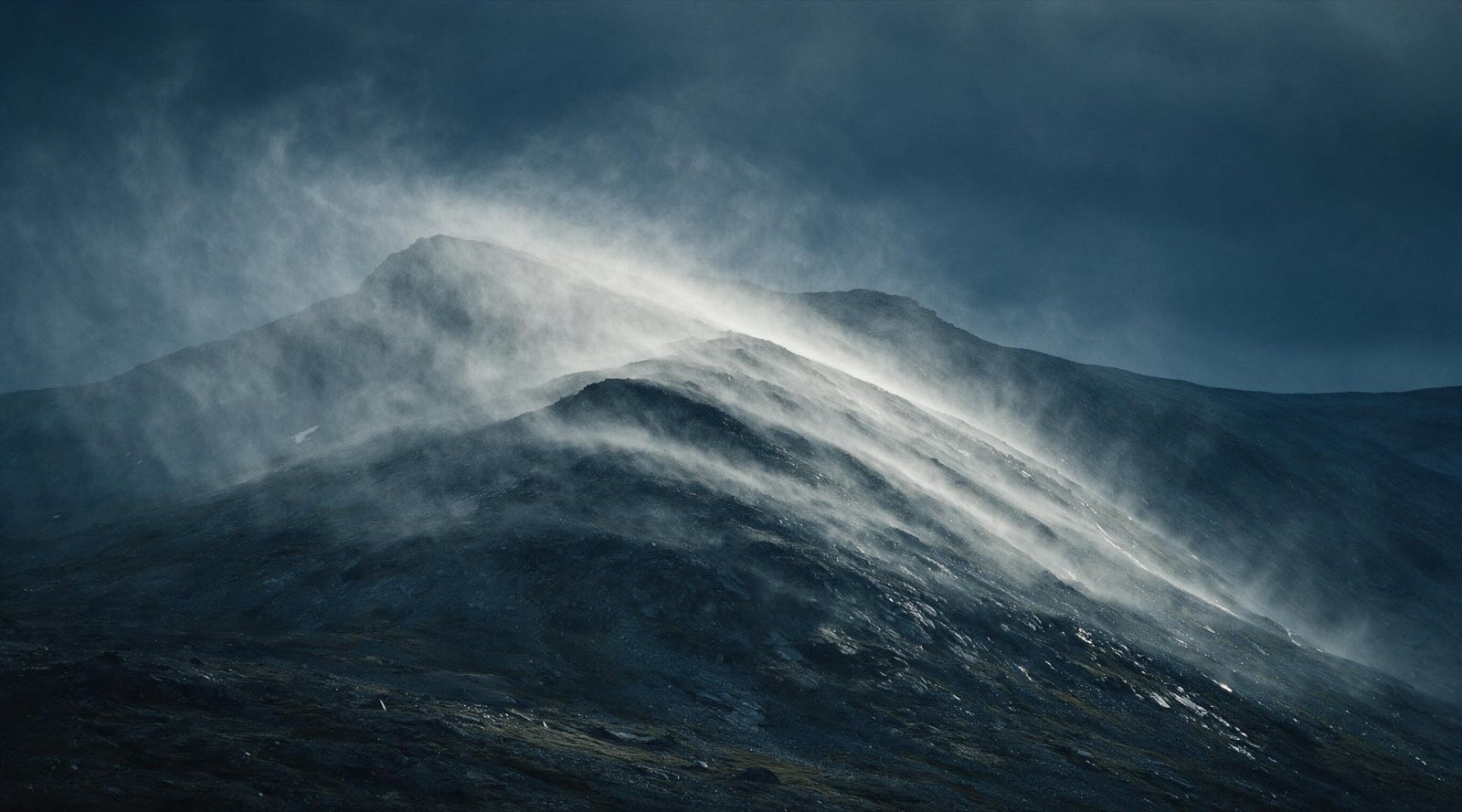 A rain squall sweeping across a slate mountain ridge