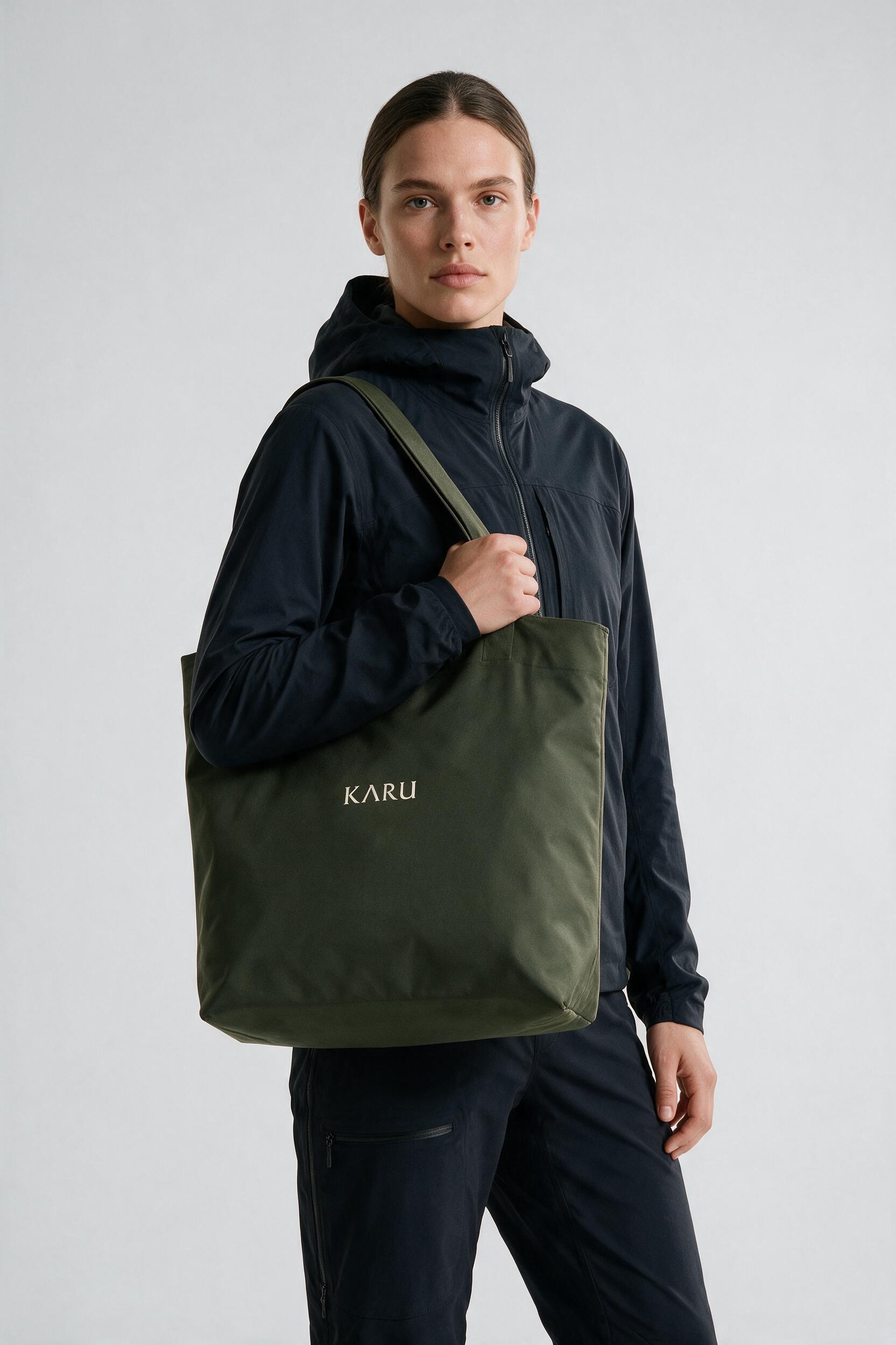Nikka Tote pack in deep moss, worn on the back, studio product shot on a seamless neutral ground
