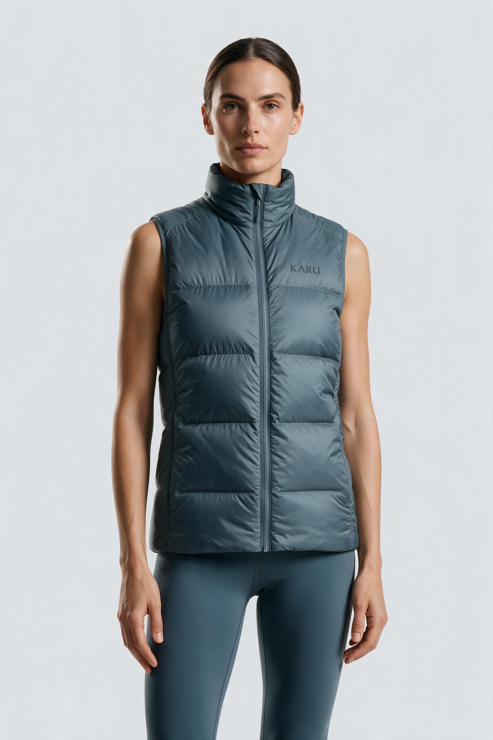 Sitas Vest in slate blue-grey, worn by a model, studio product shot on a seamless neutral ground
